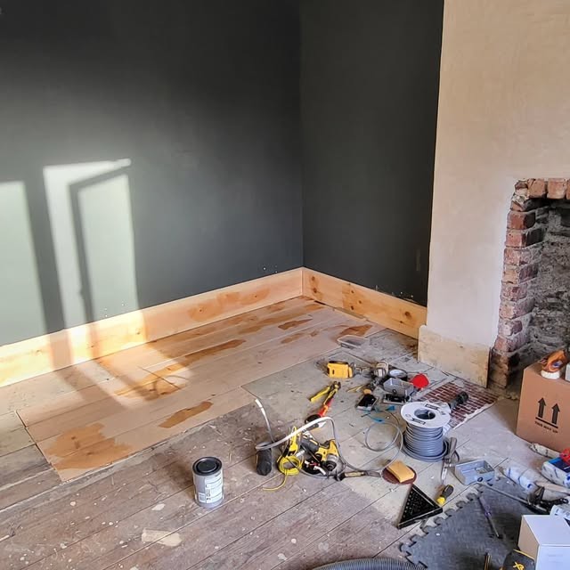 Interior room with finished dark wall and timber skirting, tools on the floor